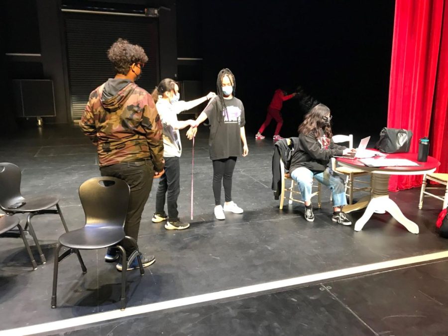 Senior Yen Lam takes Schekanias measurements as the costume department prepares for the April production.
